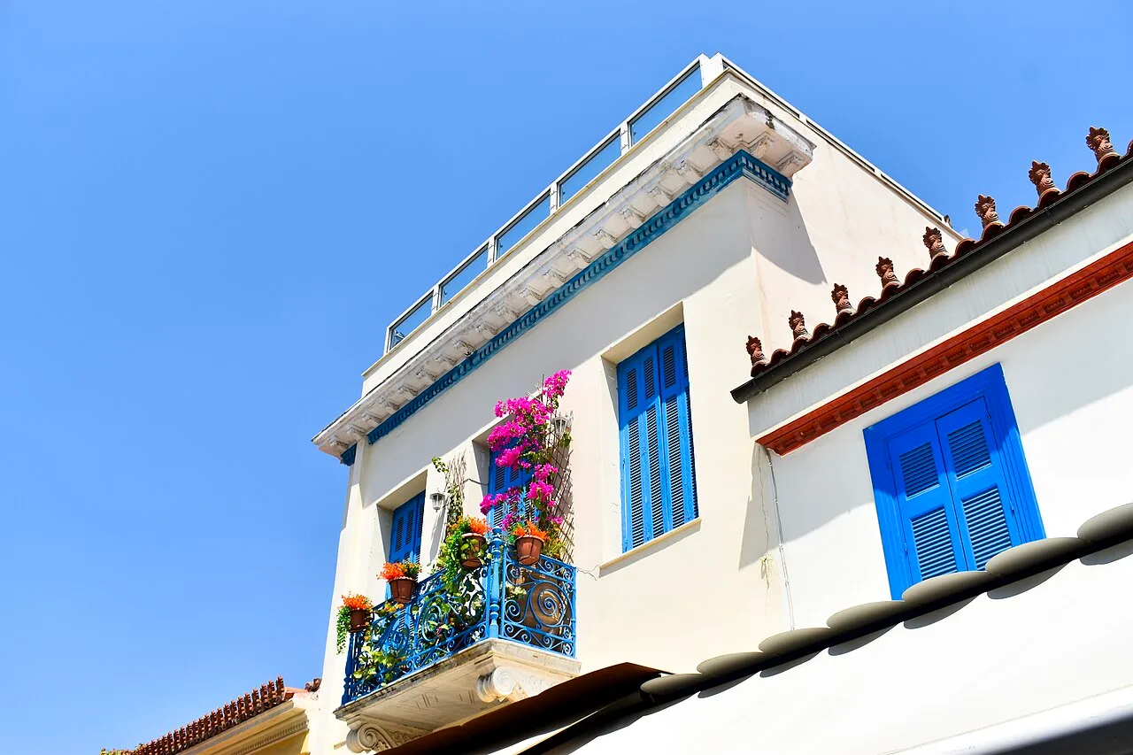 Façade blanche aux volets bleus et balcon fleuri dans le quartier de Plaka, à Athènes